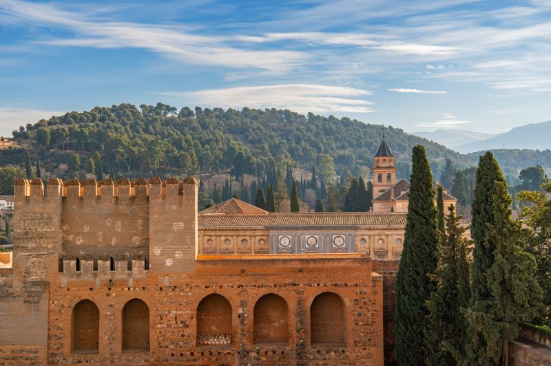 Sonnenuntergang über der Plaza de España in Sevilla mit goldenen Reflexionen im Wasserkanal und leuchtender Architektur