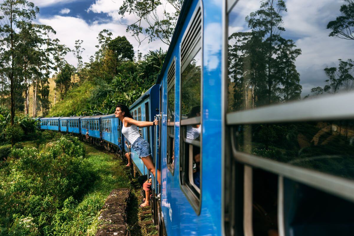 Eine junge Frau reist mit dem Zug durch eine malerische Berglandschaft in Asien. Junge Frau reist mit dem Zug durch die Berge in Sri Lanka.