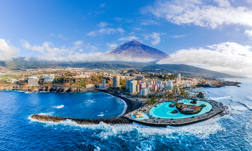 Luftaufnahme von der Insel Teneriffa, vom Meer auf das Land gesehen, mit der Stadt Santa Cruz de Tenerife im Vordergrund und dem Vulkanberg Pico del Teide im Hintergrund.