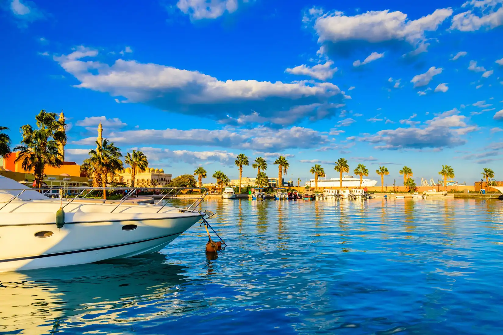 Blick auf die Hurghada Marina vom Wasser aus. In der Marina liegen Boote an. Im Hintergrund ist die Pormenade zu sehen.