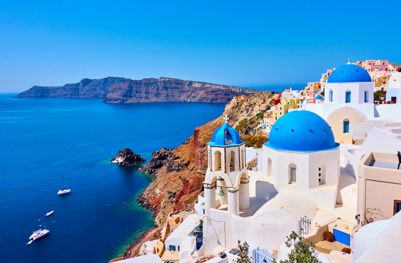 Blick von der Insel Santorini auf die Stadt Oia mit ihren charakteristischen weißen Häusern und das Meer.