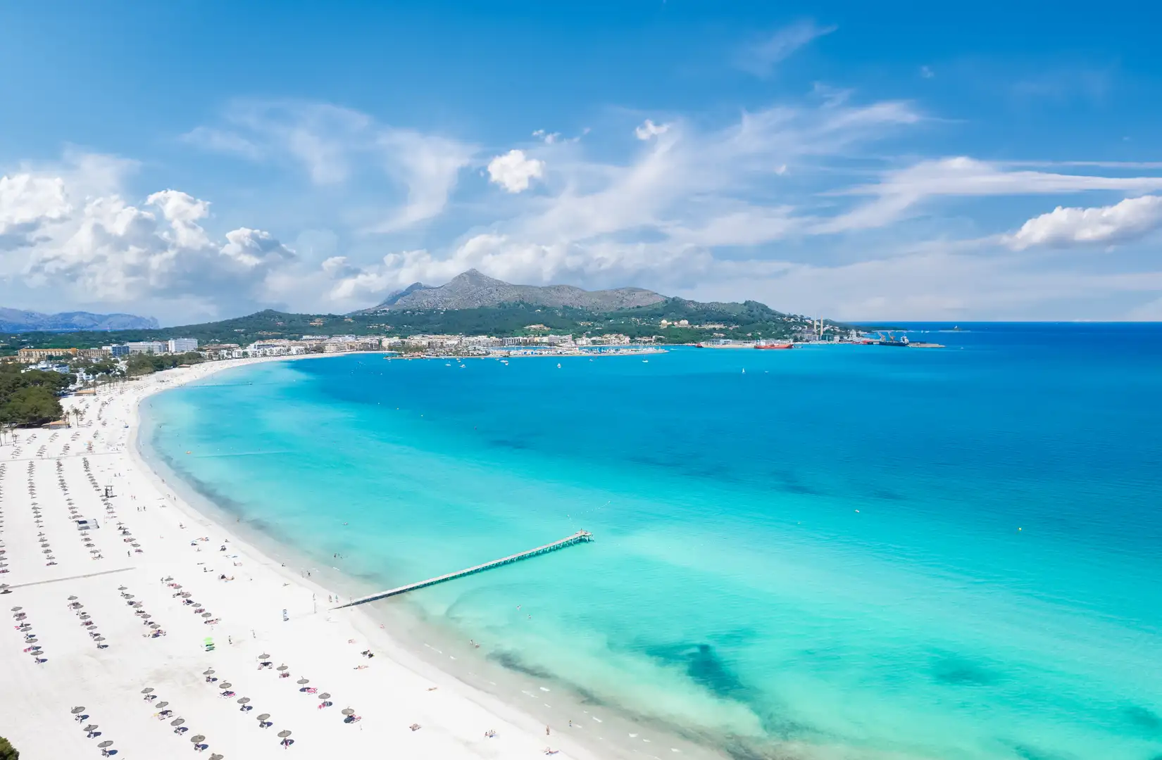 Drohnenfoto von Platja de Muro in der Bucht von Alcudia auf der balearischen Insel Mallorca in Spanien an einem schönen Sommertag. Rechts das türkisfarbene Meer und links der nahezu weiße Sandstrand.
