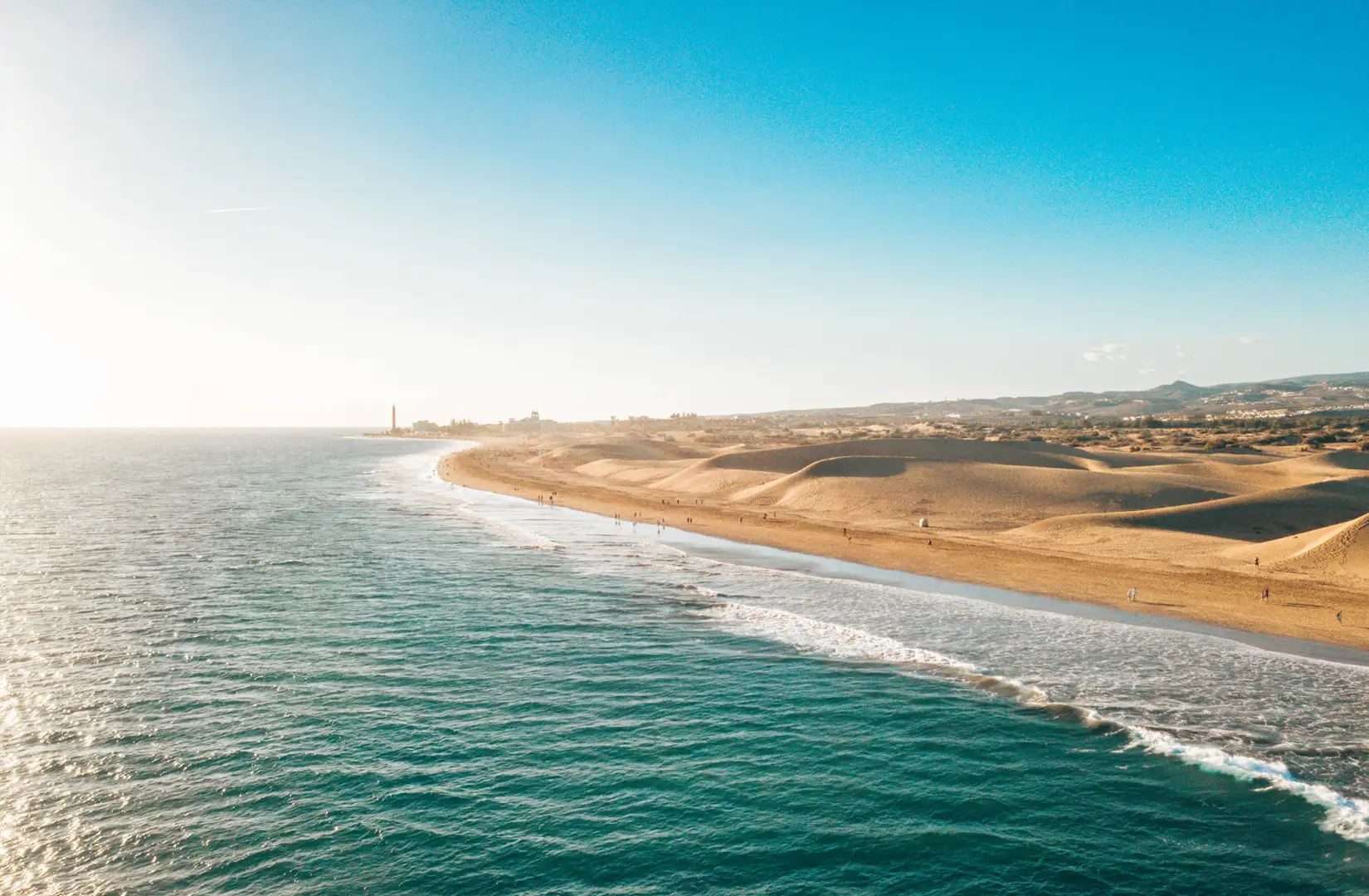 Luftaufnahme auf den goldgelben Strand von Maspalomas mit seinen Sanddünen, vom Meer aus gesehen, auf Gran Canaria, die zu den kanarischen Inseln gehören, an einem sonnigen Sommertag. 