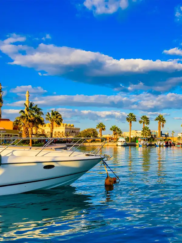 Blick vom Wasser aus auf die Strandpromenade mit Läden in der ägyptischen Touristen-Stadt Hurghada an einem sonnigen Tag.