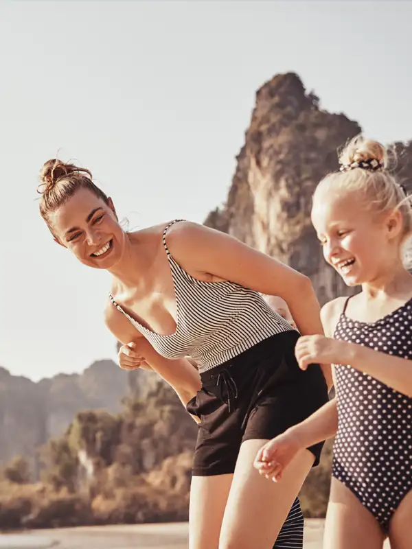  Mutter und mit zwei kleinen Kinder gehen zusammen am Strand spazieren und haben eine gute Zeit im Urlaub.