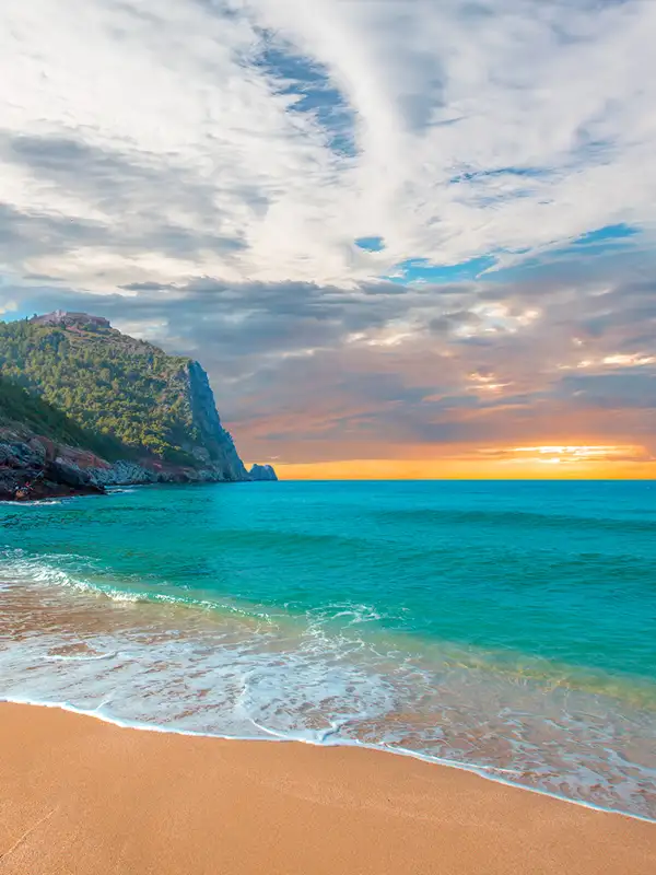 Strand von Kleopatra mit Meer und Felsen bei Sonnenuntergang auf der Halbinsel Alanya.