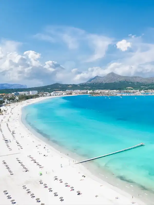 Drohnenfoto von Platja de Muro in der Bucht von Alcudia auf der balearischen Insel Mallorca in Spanien an einem schönen Sommertag. Rechts das türkisfarbene Meer und links der nahezu weiße Sandstrand.
