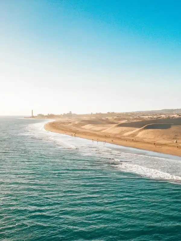 Luftaufnahme auf den goldgelben Strand von Maspalomas mit seinen Sanddünen, vom Meer aus gesehen, auf Gran Canaria, die zu den kanarischen Inseln gehören, an einem sonnigen Sommertag. 