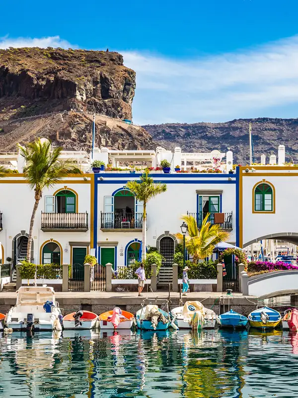 Traditionelle bunte Gebäude mit Booten davor in der Marina von Puerto de Mogan auf Gran Canaria